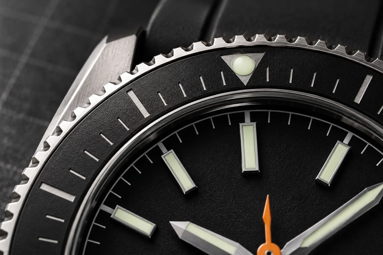 Close-up of the GAUGE-02 bezel graduations and lume pip in raking light, the orange seconds hand at the centre.