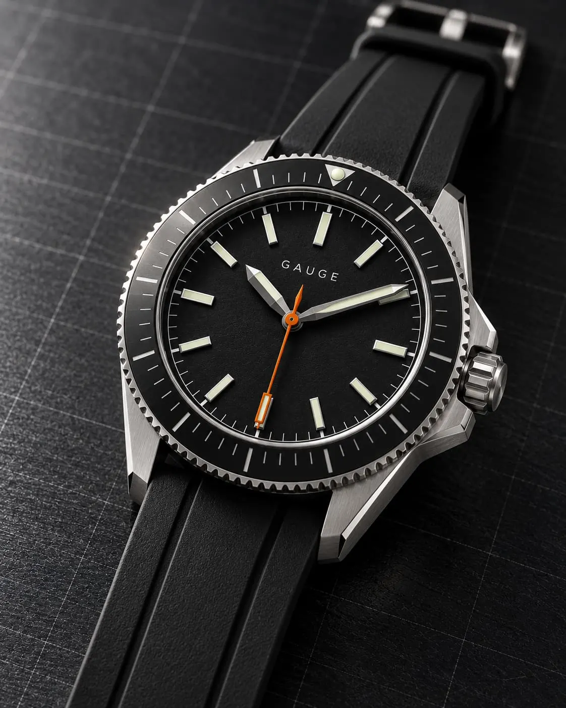 GAUGE-02 Depth, black dial and bezel with an orange seconds hand, on a black rubber strap at three-quarter angle on a dark grid mat.