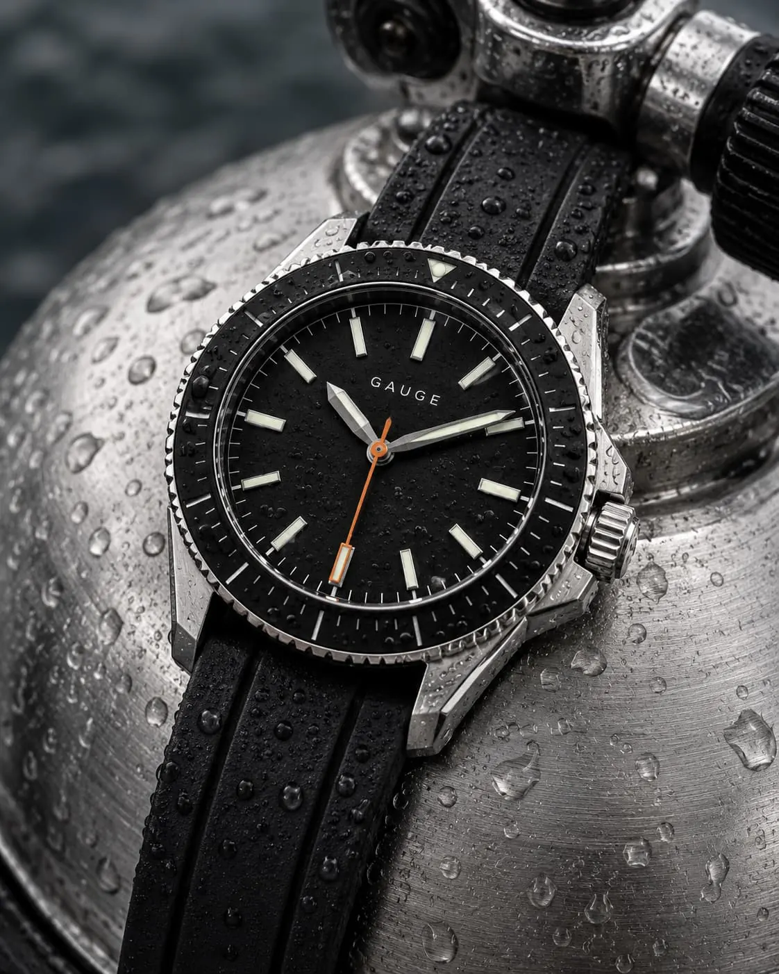 GAUGE-02 Depth on its rubber strap, beaded with water, lying on the shoulder of a steel dive cylinder.